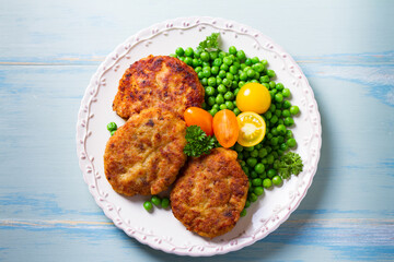 Fish burgers with vegetables on white plate. Fish patties or cakes. High angle view