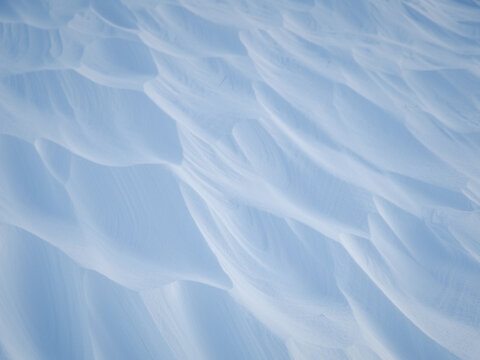 Snow texture. Wind sculpted patterns on snow surface. Wind in the tundra and in the mountains on the surface of the snow sculpts patterns and ridges (sastrugi). Arctic, Polar region. Winter background - Powered by Adobe