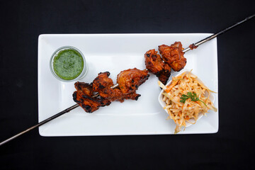 Chicken boti kabab skewer with sauce and salad in plate Top view of Bangladeshi food