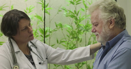 Female doctor consoling senior male patient showing distress in medical office, emphasizing empathy...