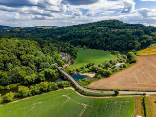 Fototapeta premium Scenic English countryside with a historic bridge over a winding river in summer.