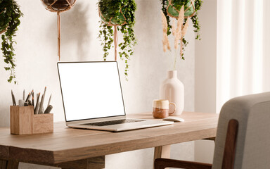 Laptop with blank screen mockup on a wooden desk - modern workspace in boho style surrounded by...