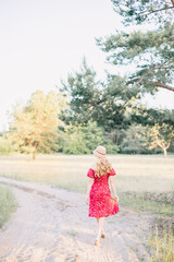 Naklejka premium Woman in Red Dress Walking in Sunny Park