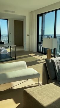 Bright Modern Interior Design with White Chaise Lounge and Neutral Tones Featuring Large Windows and an Urban View on a Sunny Day