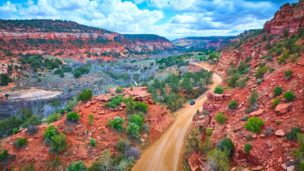 Aerial Red Rock Canyon with Winding Road and Blue Vehicle Utah Wilderness