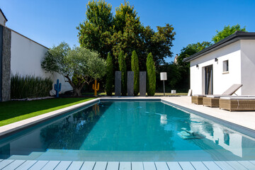 Piscine contemporaine intégrée dans un jardin moderne avec pelouse soignée et aménagement paysager élégant.