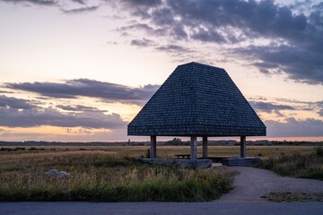 Serene pavilion at sunset in a field.