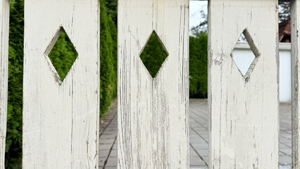 Old white wooden fence with diamond shaped cutouts, close up rustic texture background