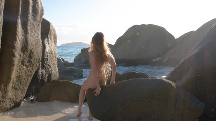 Slow motion 4K video of a woman in a gold bikini enjoying a sunny vacation in the Seychelles.