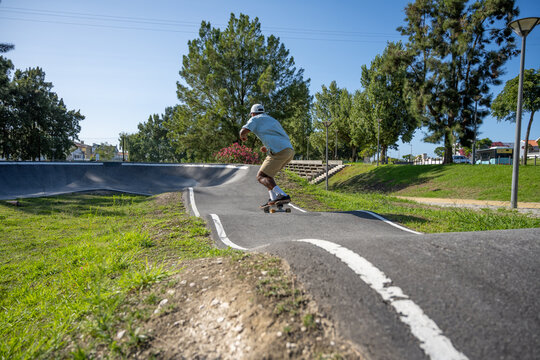 A young Black man riding a skateboard at a pump track