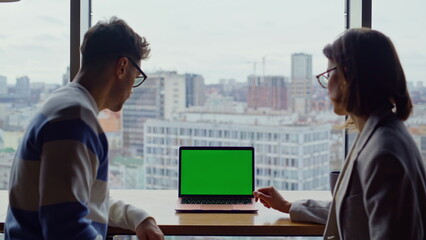 Two teammates looking greenscreen laptop working panoramic hall together closeup
