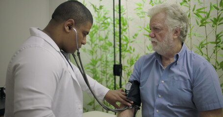 Healthcare professional measuring blood pressure of senior male patient during medical examination...