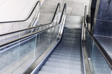 Modern escalator in shopping mall interior. Moving staircase with glass railing. Empty escalator...