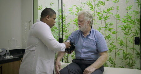 Healthcare worker concluding blood pressure assessment and discussing results with elderly male...