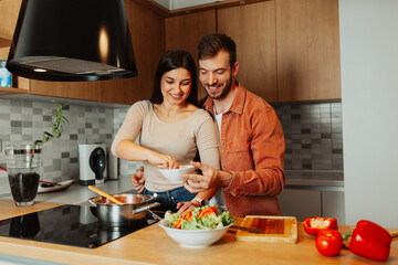 Happy couple cooking together in modern kitchen, preparing meal and enjoying domestic life