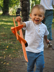little boy holding orange toy airplane in hand