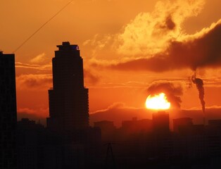 the setting sun goes into the clouds against the backdrop of high-rise buildings