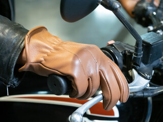 close-up of a motorcyclist's hand dressed in a brown leather glove