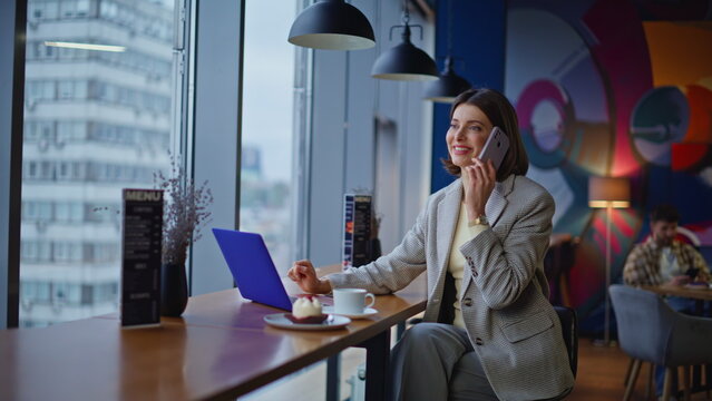 Confident manager calling smartphone in cafe bar counter near panoramic window