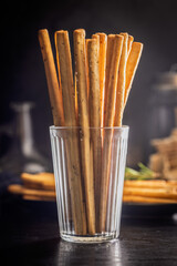 Crispy grissini breadsticks in cup on black table.