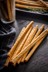 Crispy grissini breadsticks on black table.