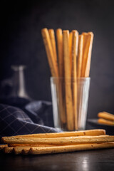 Crispy grissini breadsticks on black table.