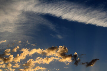 A dramatic sky, with dark clouds contrasting against a wispy contrail