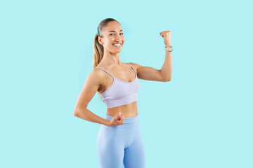 Athletic young woman on blue background shows biceps, close-up. Portrait of trainer girl in...