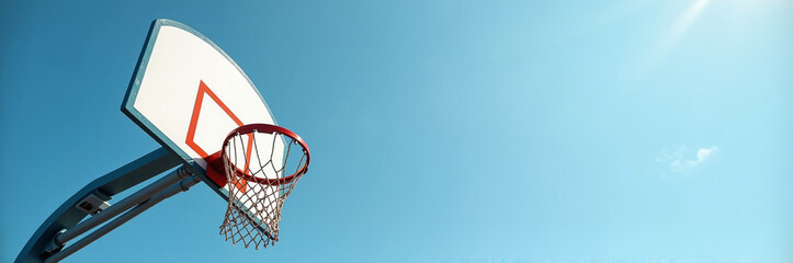 Basketball hoop against bright blue sky viewed from below, featuring net, backboard, and mounting hardware. School sport is a great way to get exercise and meet new friends.