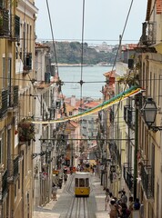 A yellow tram-lift passes through a narrow street in Lisbon. Lisbon landmark, Portugal