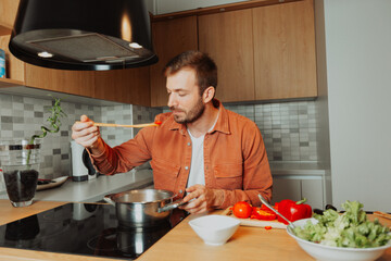 Young man cooking soup in a modern kitchen. He preparing a homemade meal with fresh ingredients