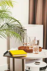Cozy living space with a tray of glasses, a notebook, and a plant near a modern device
