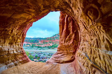 Red Sandstone Cave Interior with Swirling Patterns and Desert Landscape Utah