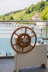 Wooden ship wheel on ferry deck with lake view