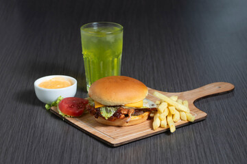 crispy taza bbq burger meal with melted cheese, lettuce leave, soft bun, soda drink, fries, mayo dip and special sauce on wooden board side view of fast food