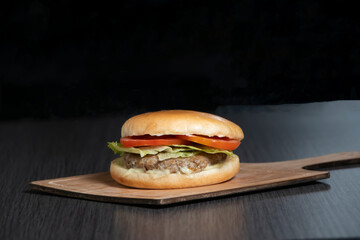 Delicious Arabic beef burger with fresh lettuce and tomato on a wooden board side view of American food