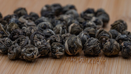 Macro Close-up of Dried Jasmine Tea Pearls on a Bamboo Surface