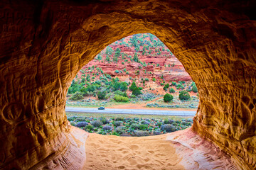 Sandstone Cave Window Over Red Rocks and Desert Road Utah Adventure Scene