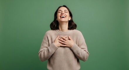 Joyful woman laughing with genuine happiness, expressing heartfelt emotion and gratitude with hands on her chest against a serene green background