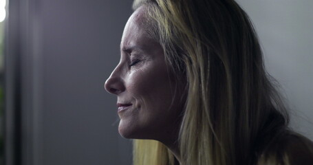 Close-up of woman in clinic looking off to the side with intense, emotional expression, IV bag in...