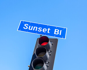 Close-up of a Sunset Blvd sign against a blue sky in Los Angeles, CA.