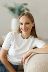 Happy woman using laptop sitting on cosy sofa