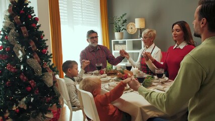 Family praying before christmas dinner - Powered by Adobe