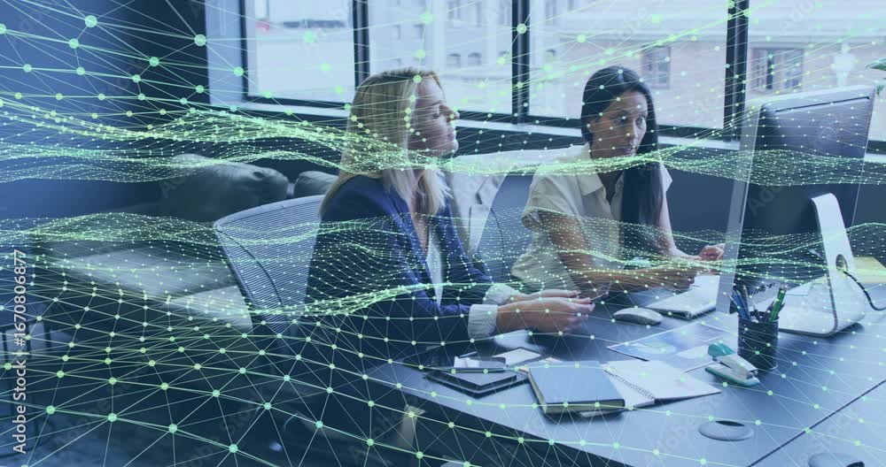 Poster analyzing business report, colleagues pointing at screen while viewing data lines overlaying desk