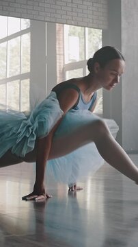 Graceful ballerina makes leg-split on floor stretching body