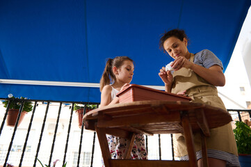 Mother and Daughter Gardening Together on a Sunny Balcony