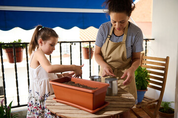 Mother and Daughter Gardening Together on a Sunny Balcony