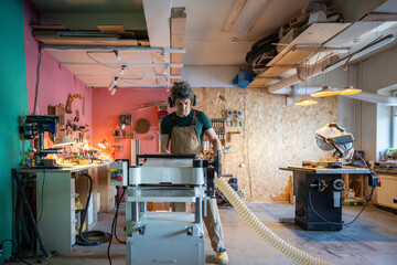 Concentrated craftsman working on band saw machine, making woodwork project for customer handover...