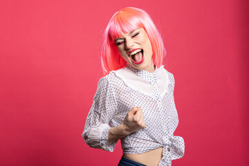 Joyful caucasian lady expressing excitement with mouth open and fist raised, standing isolated over pink background. Beautiful happy woman filled with enthusiasm, celebrating good news and success.