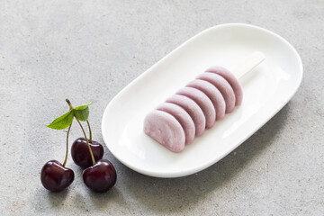 Cherry ice cream of modern shape. On a wooden stick. Close-up